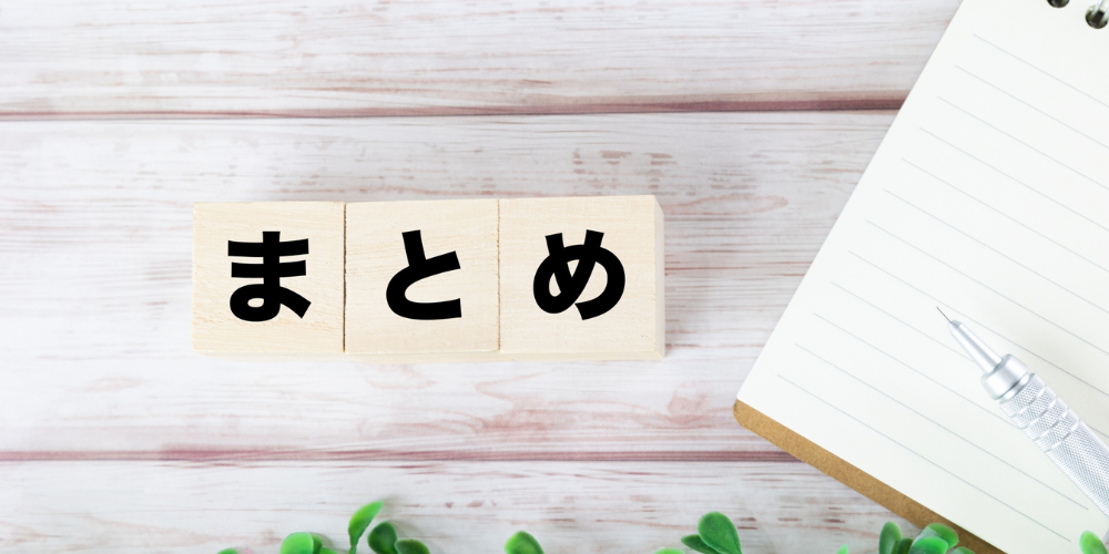 ひらがなで「まとめ」と書かれた木製ブロック。右側にノートとペンが置かれている。