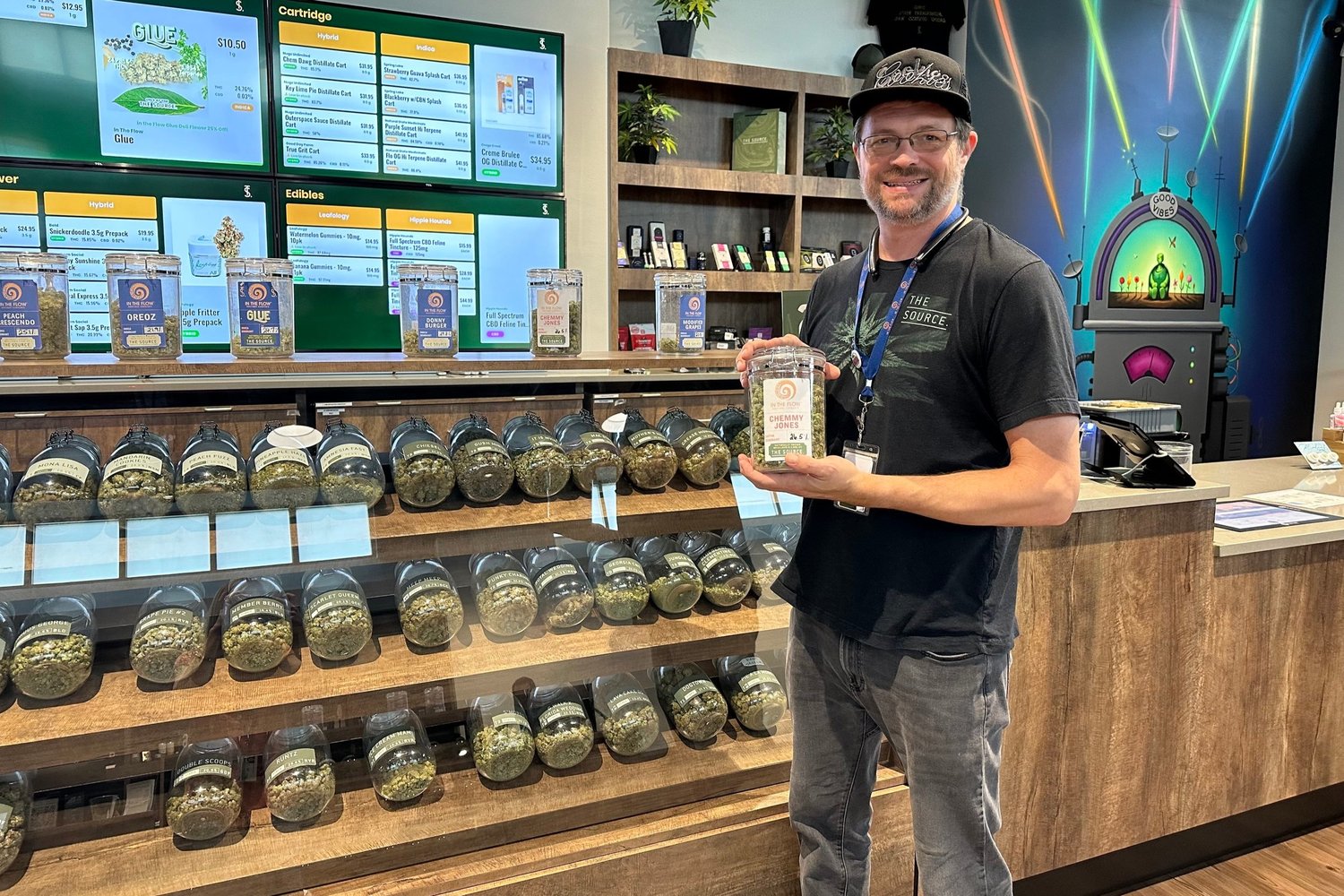 Budtender, Shaun Forrester, holds a jar of Chemmy Jones flower, available exclusively at The Source cannabis dispensary in Rogers, Arkansas.