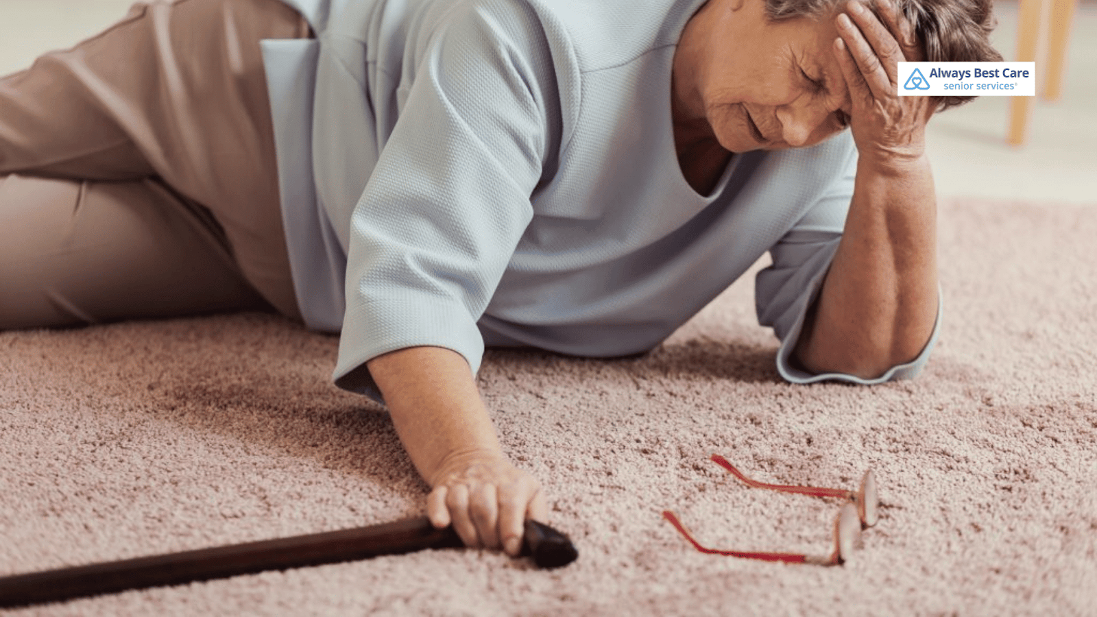 This image depicts a senior woman on the ground holding a cane with glasses fallen