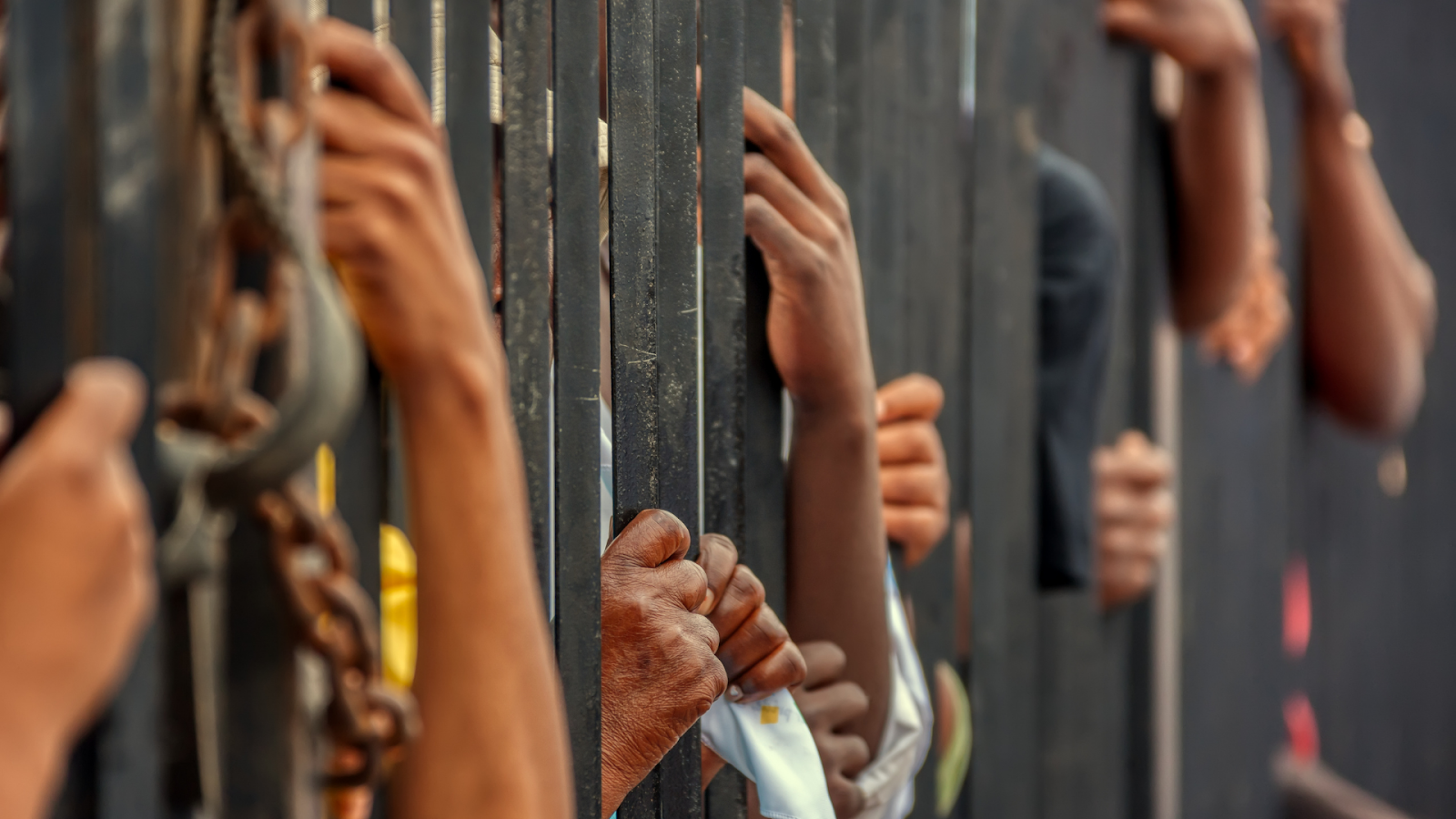 (people behind a fence indicating detainment)