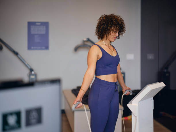 A woman using a sleek, modern body composition analyzer, emphasizing precision and technology in health assessment.