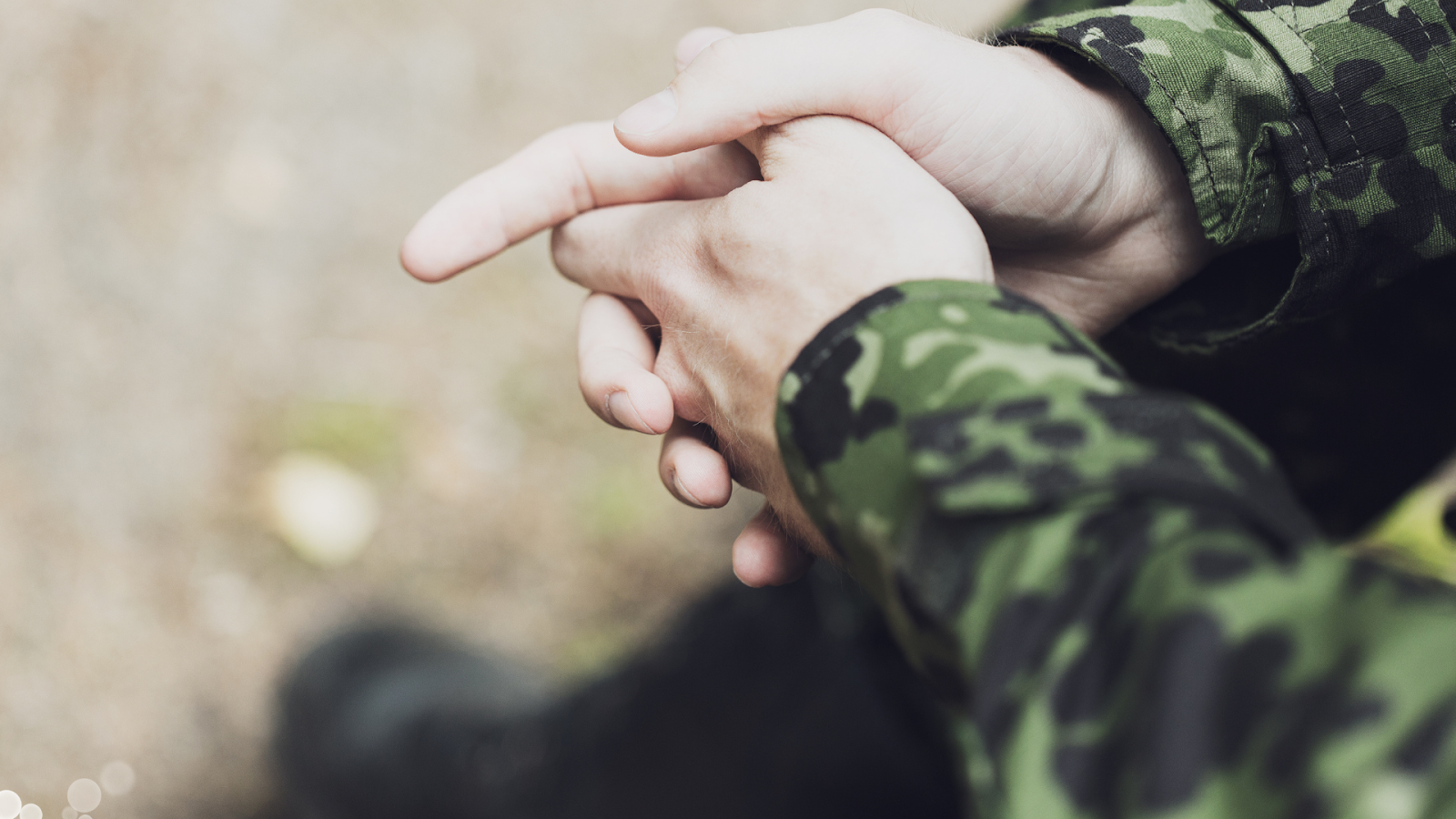 Person sitting in military clothes with their arms closed // Healthier Veterans Today