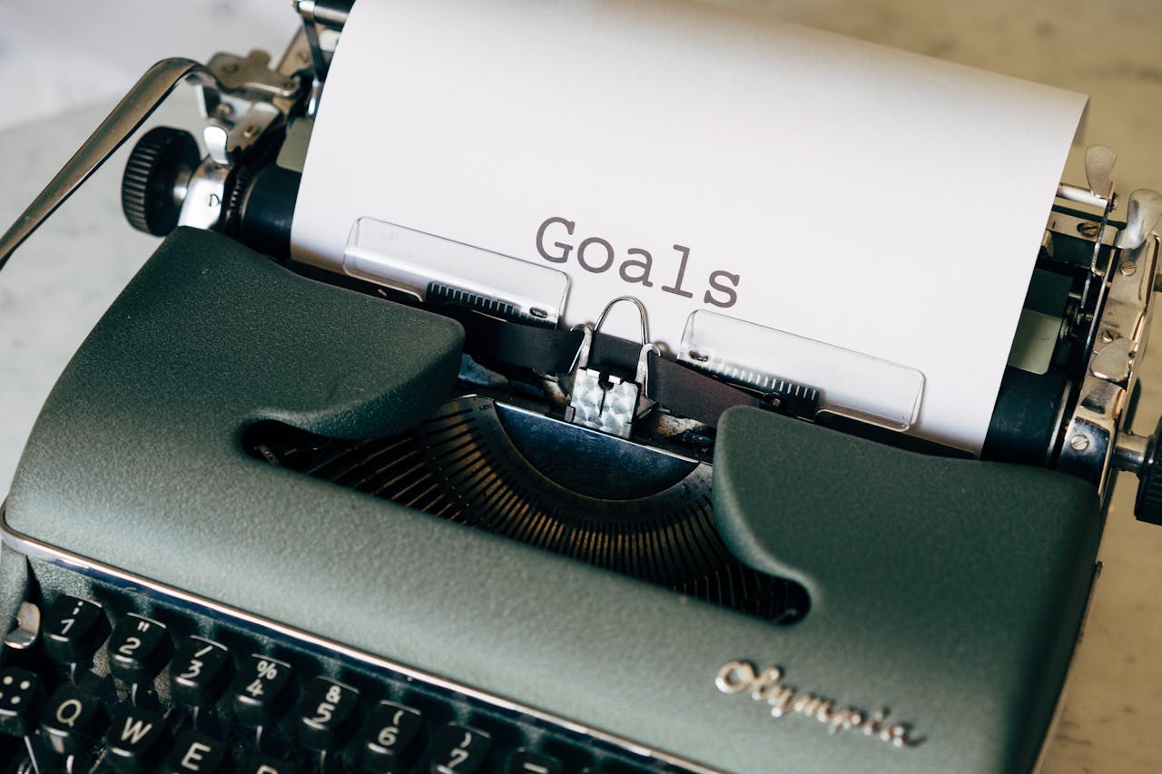 A vintage typewriter with a sheet of paper displaying the word "goals" typed out.