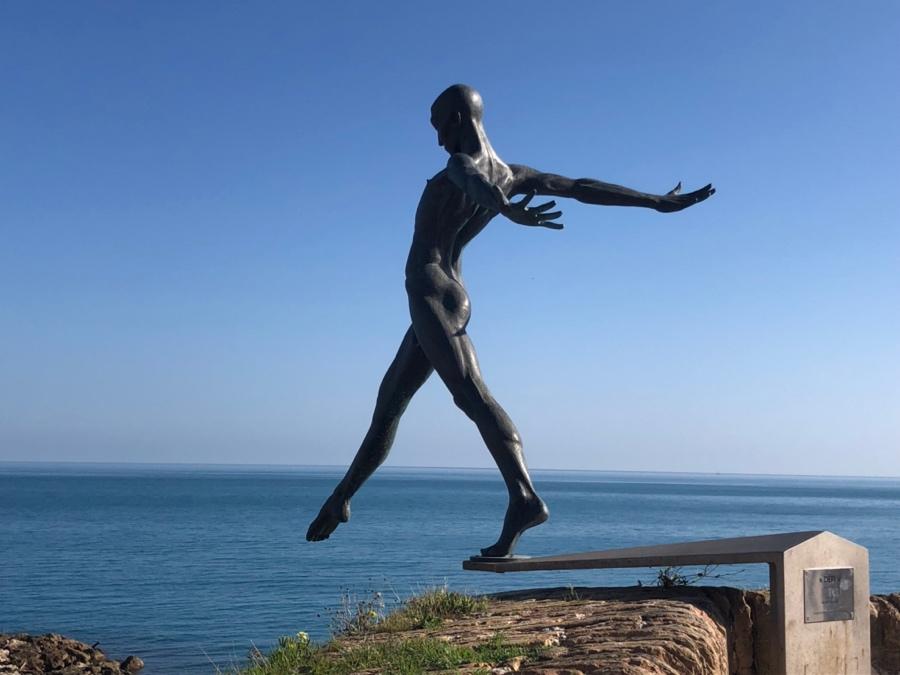 A statue of a person jumping off a rail

Description automatically generated