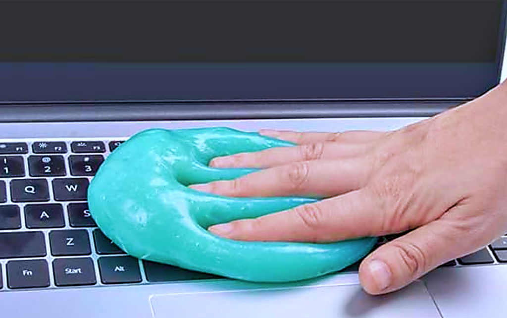 Person pressing a blue cleaning gel on a-laptop keyboard