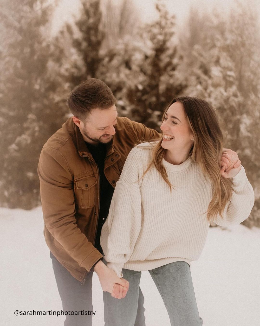 winter engagement photos couple smiling in the snowy forest