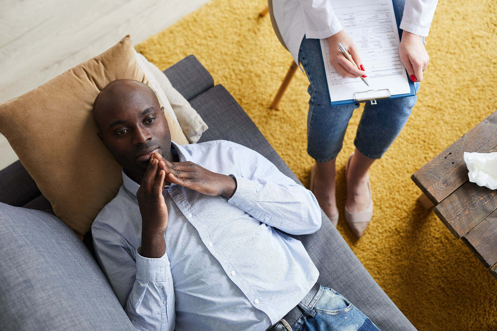 A man is lying on the couch and receiving counseling.