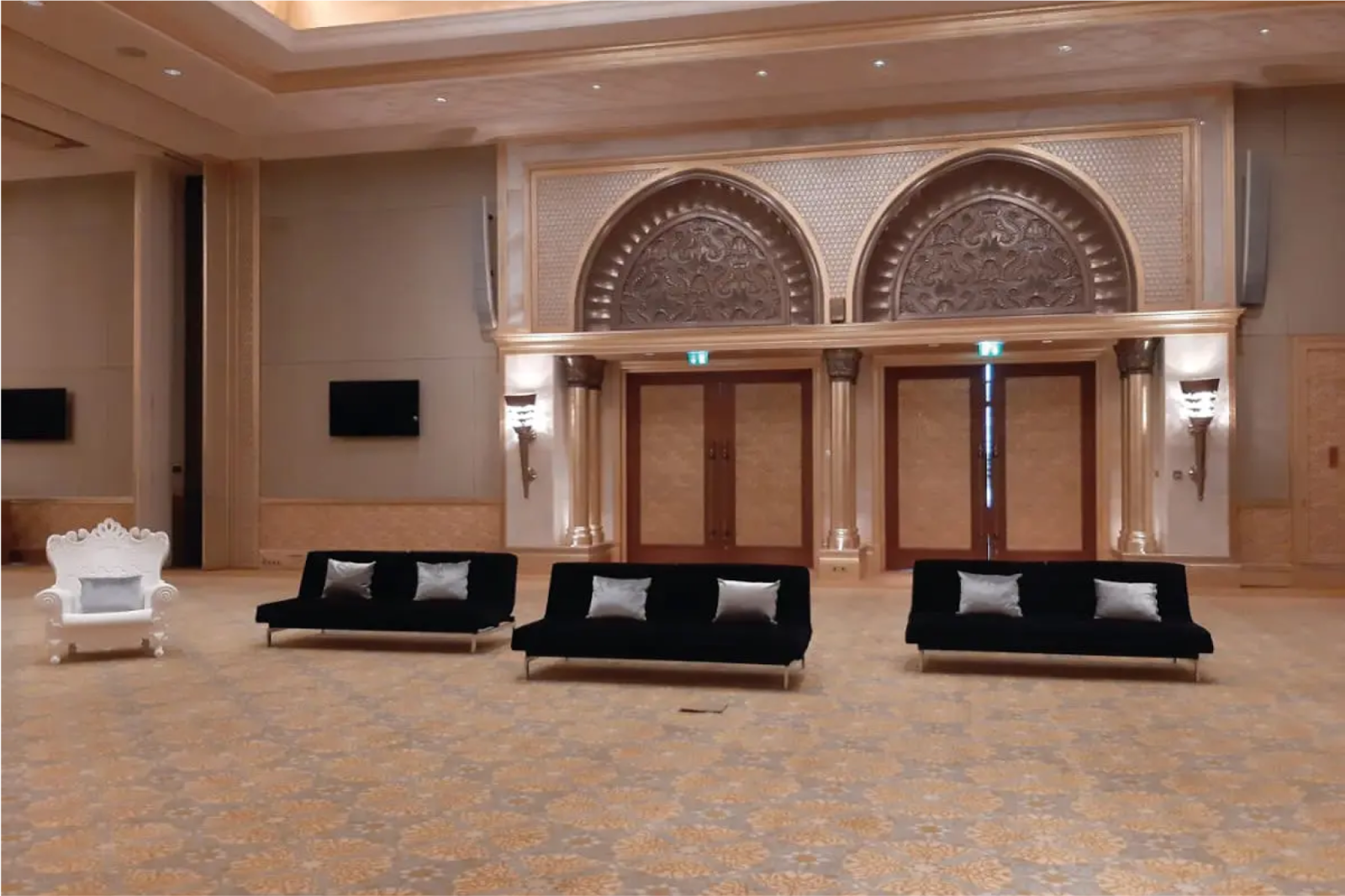 Indoor event venue with soft black velvet sofas and grand arched doors, suitable for formal gatherings.