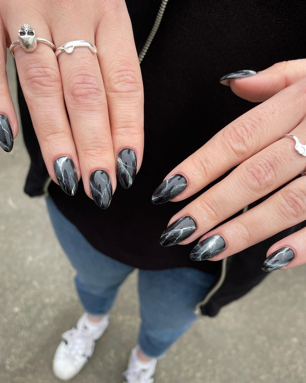Close-up of a person's hands with black nails having Black and White Marble Effect