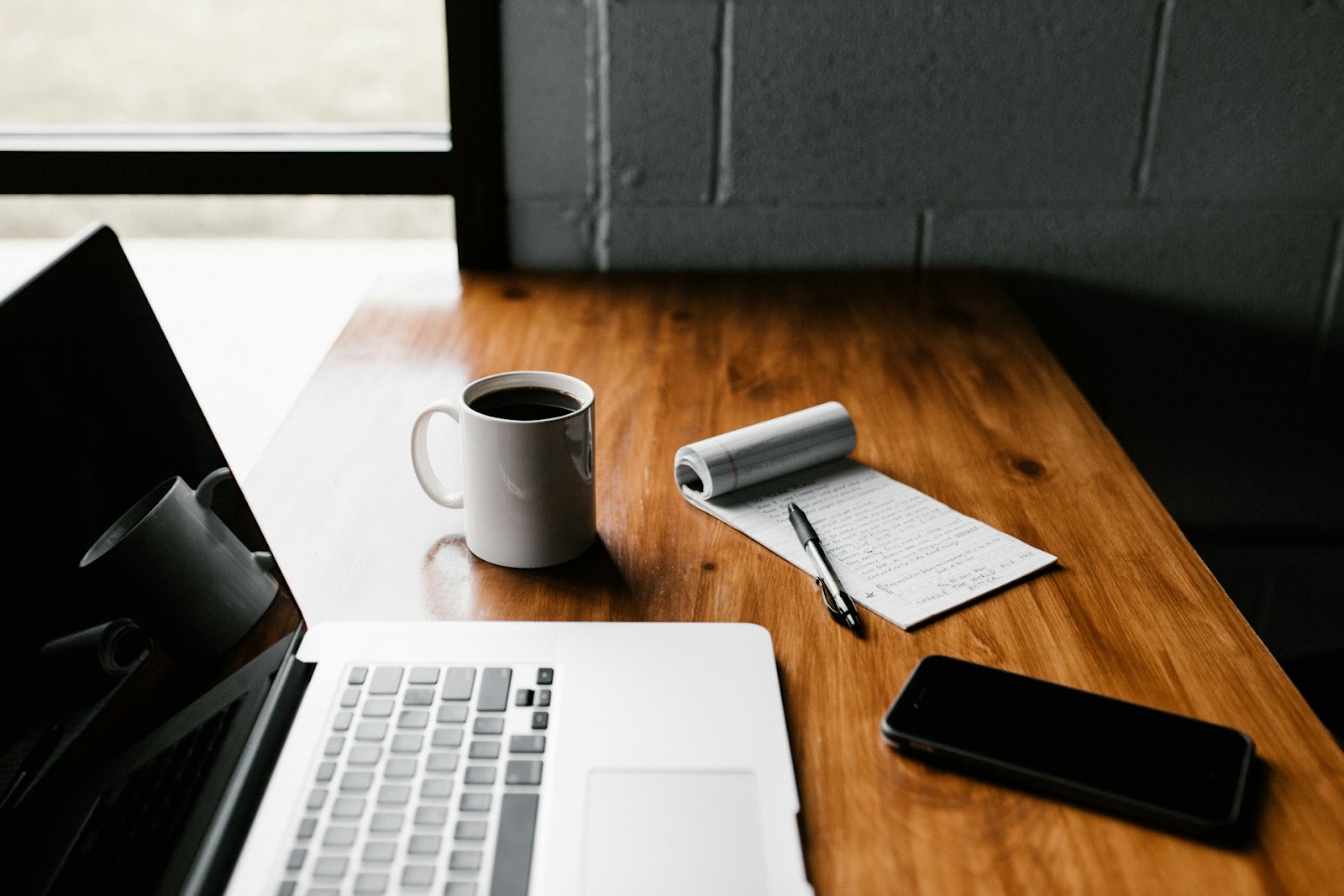 a laptop, notebook, smartphone, and cup of coffee