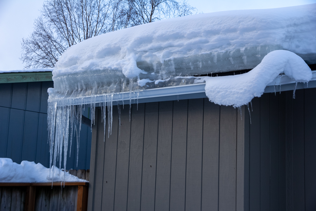 A dense layer of snow and icicles on a roof