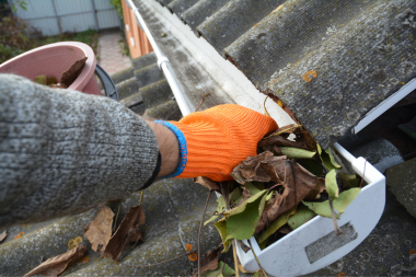 essential winterizing tips for your michigan home clearing leaves and debris from roof gutter custom built okemos