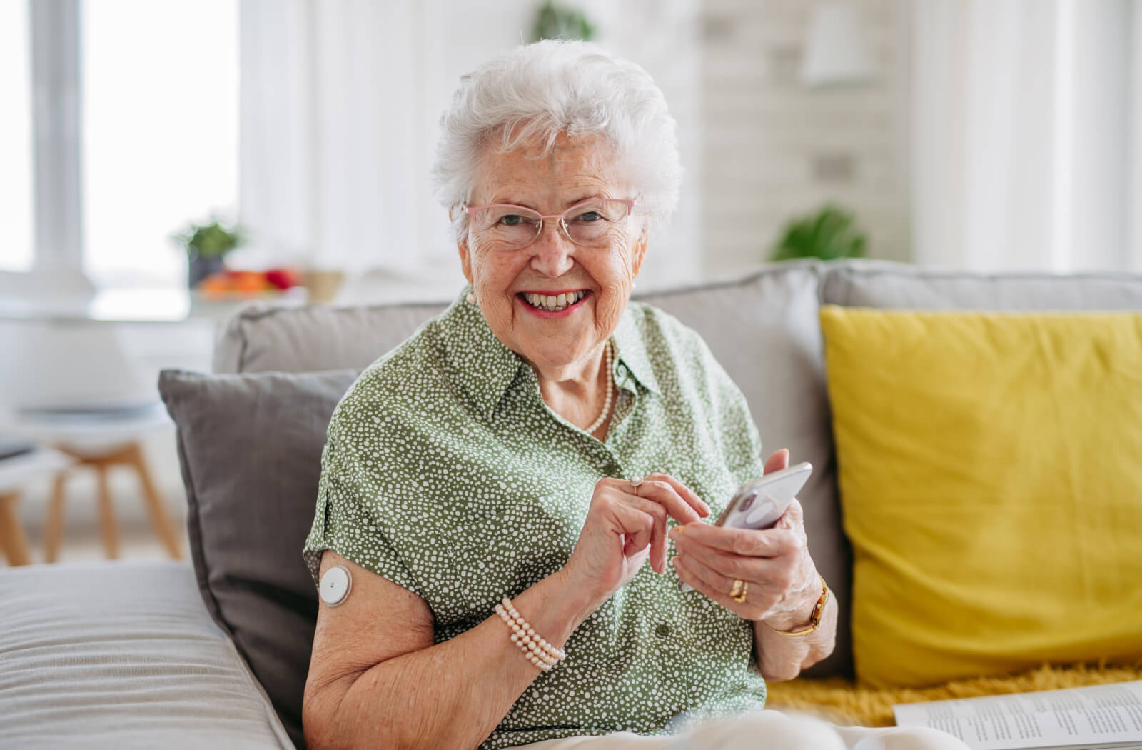 An older adult with dementia in memory care smiling at the camera after hanging up their cell phone.
