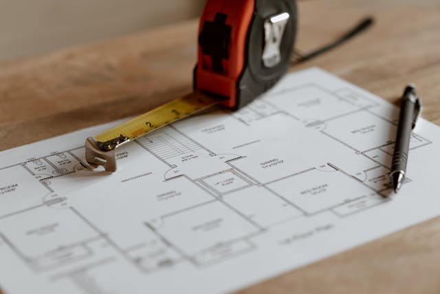 A floor plan rests on a wooden table, crafted by an esteemed architectural firm.