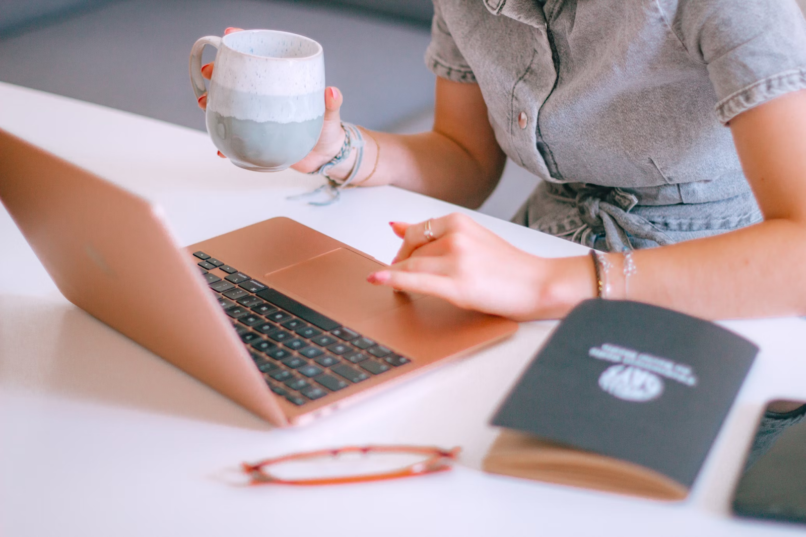 How to reference Wikipedia in academic papers. Woman sits in front of her laptop with a coffee in hand. She’s scrolling through research articles to find Wikipedia citation examples.