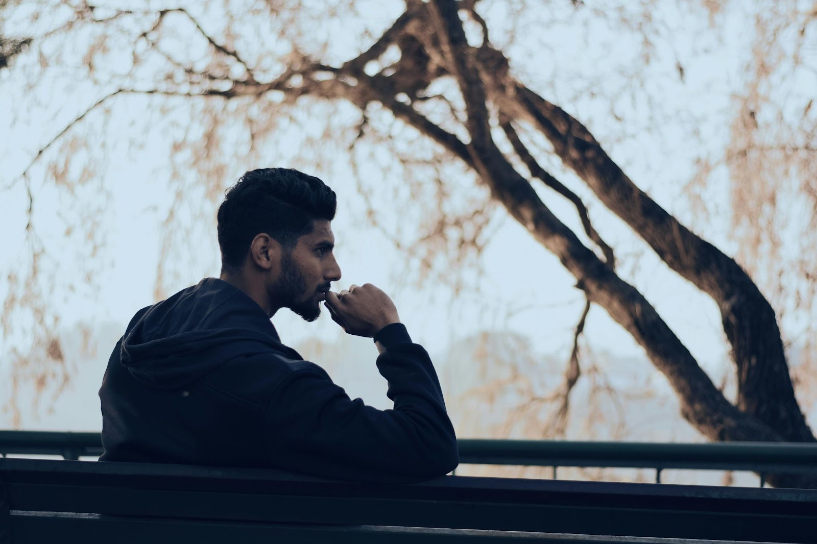 A man sitting on a park bench alone thinking