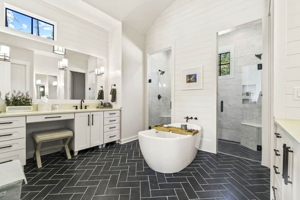 The primary bathroom is equipped with a dual sink vanity, a deep soaking tub, and a walk-in shower with two hinged doors.