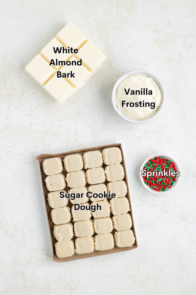 View from the upper appearance of baking ingredients on a light background: a white cur cortex block, a vanilla glaze container, a small bowl with red and green sprinkles and a sugar biscuits with squares.