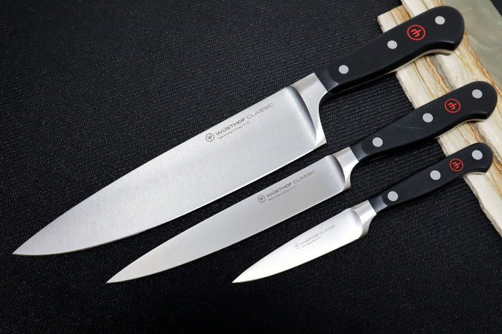 An image displaying a Wusthof Classic chef's knife set featuring three essential knives: a chef's knife, a utility knife, and a paring knife.