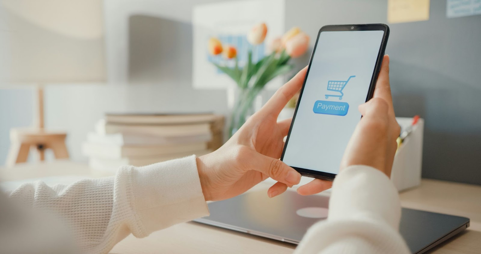 A person holding a phone with a payment logo on the screen.