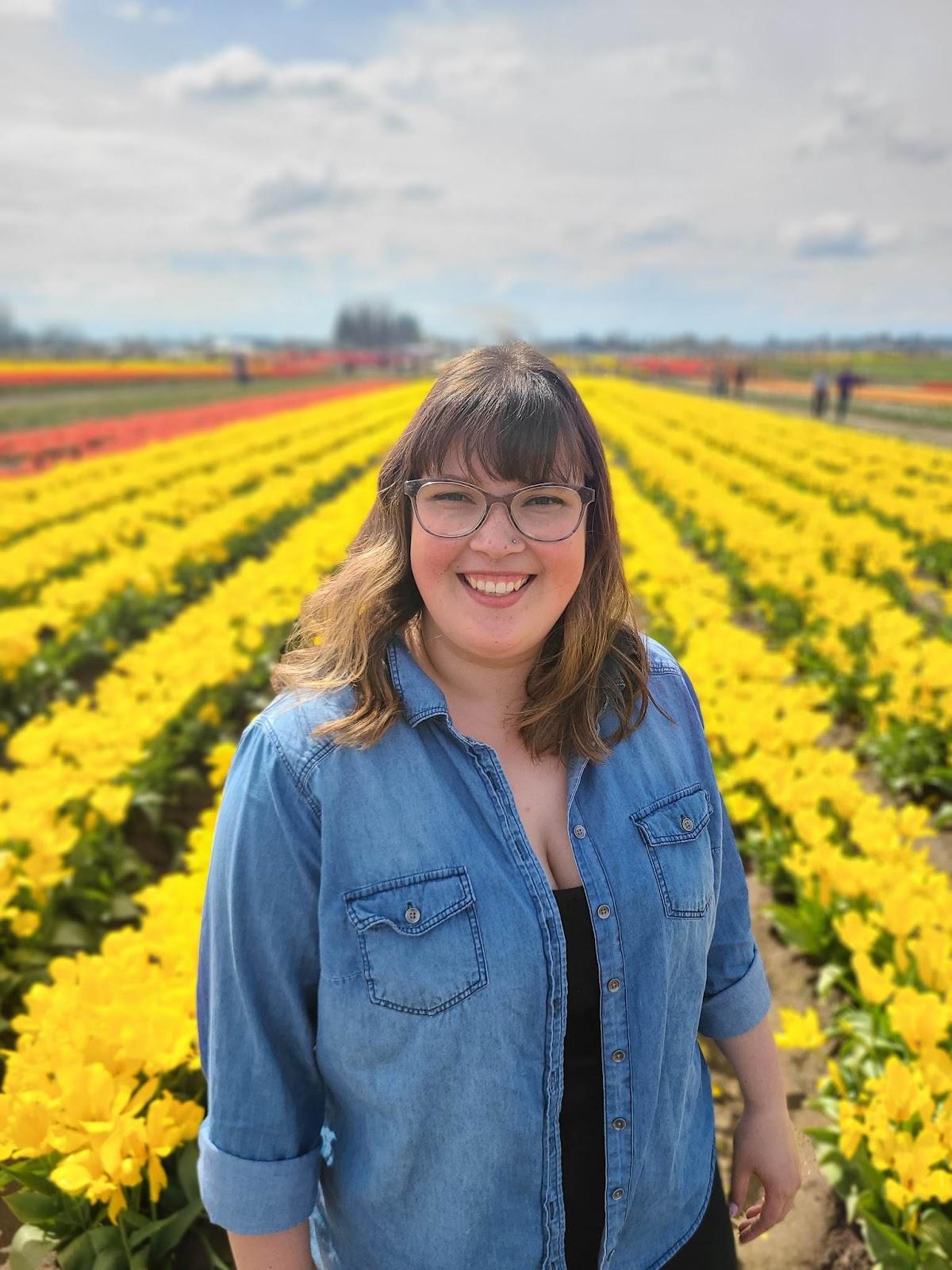 A person standing in a field of yellow flowersDescription automatically generated