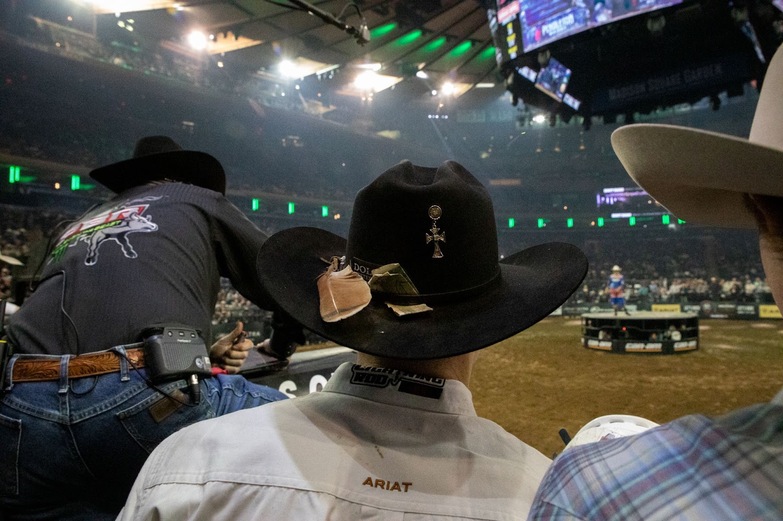 Man in black cowboy hat watches the arena.
