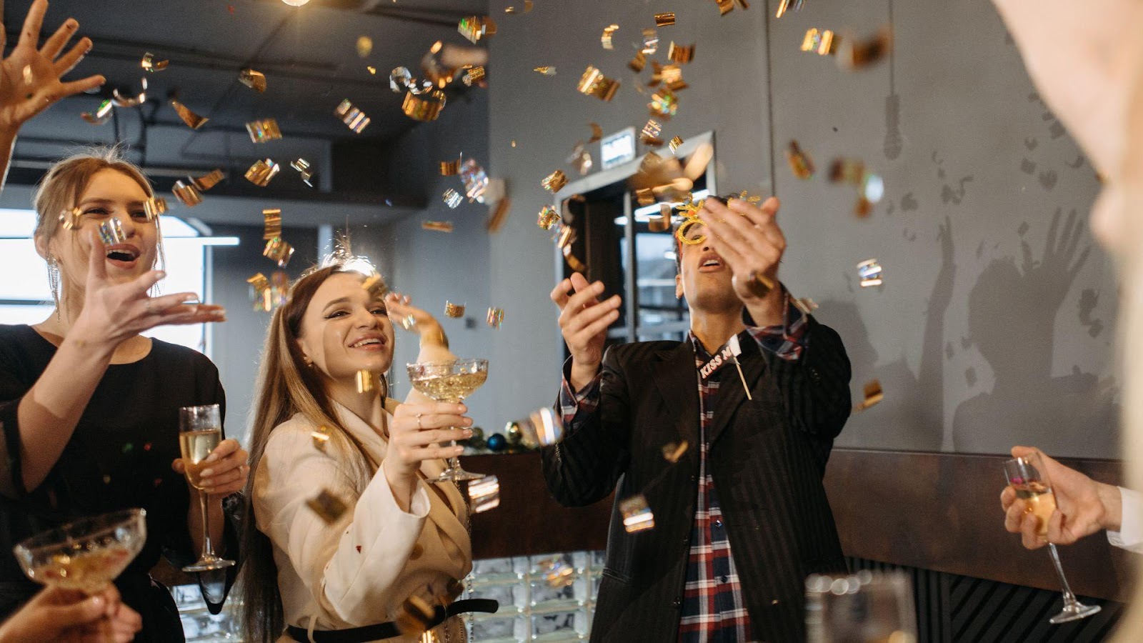 A group of coworkers celebrating in an office setting, throwing confetti and toasting with champagne, highlighting the impact of workplace celebrations on team morale and culture.