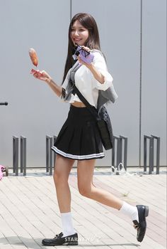 This contains an image of Sooyoung in a school uniform and holding a donut and walking down the street