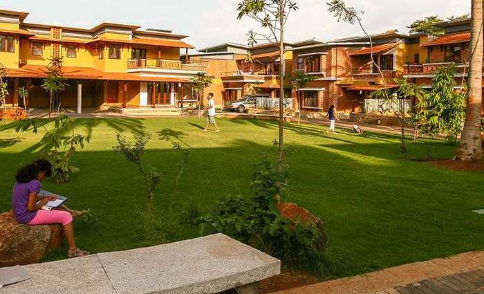 A lush green courtyard with children playing and a person sitting on a rock, sketching.