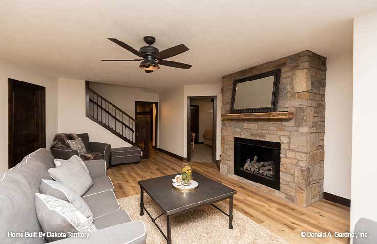 Family room with a gray sectional, a dark coffee table, and a stone fireplace topped with a large mirror.