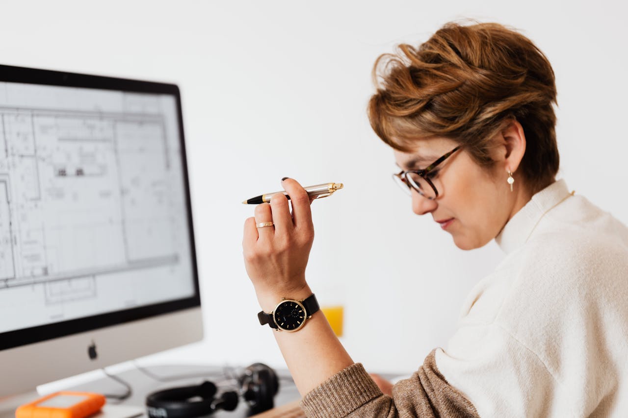 A focused female architect reviewing detailed building plans on her computer