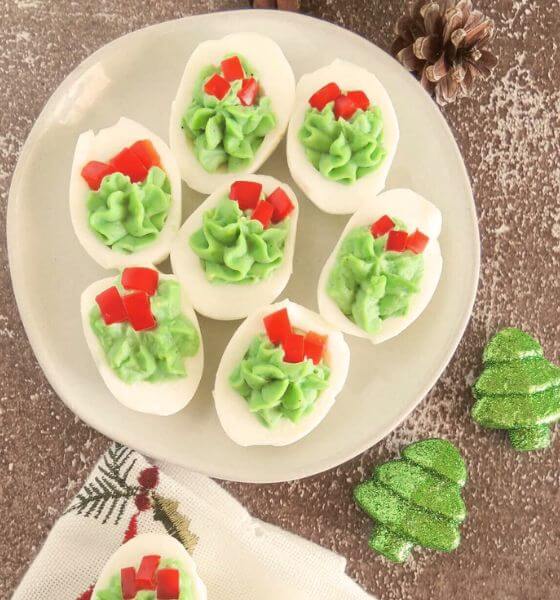 Red and green Christmas deviled eggs on a white plate