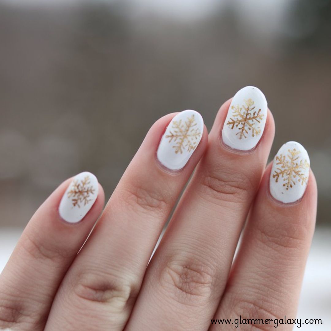 Snowflake Nails having White Nails with Gold Snowflakes
