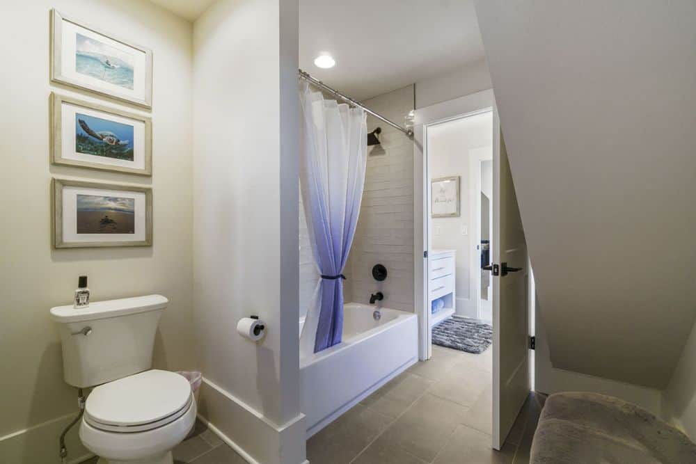 The bathroom includes a toilet area adorned with framed artworks.