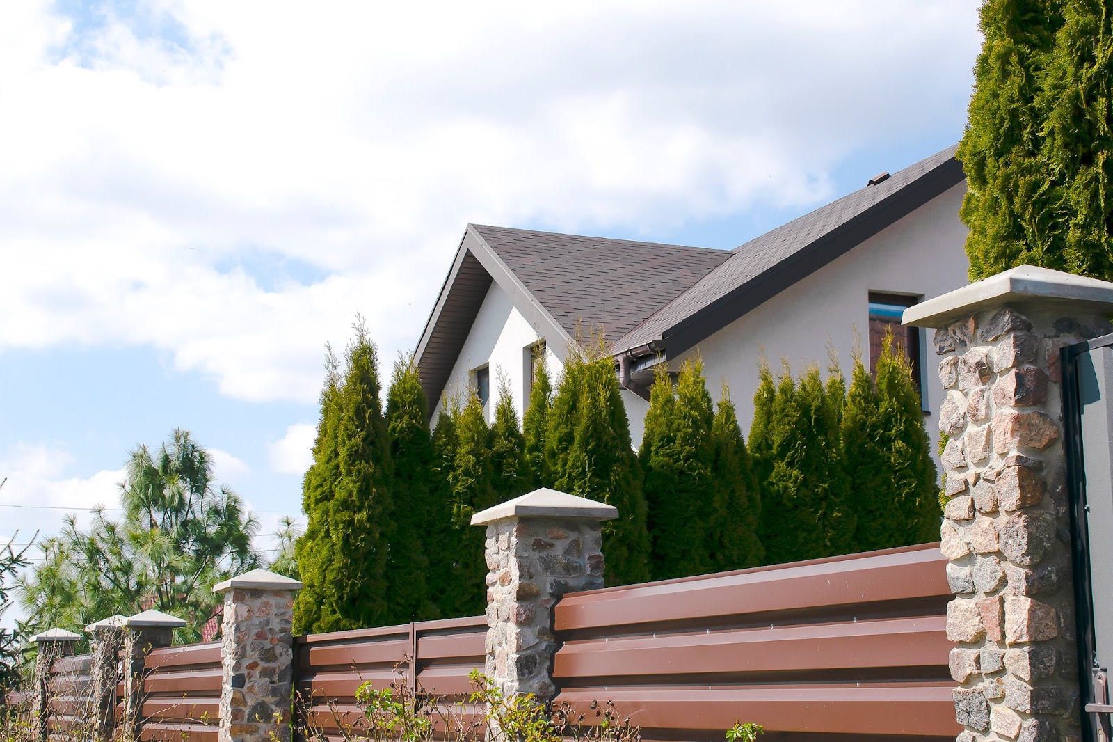 A private house backyard featuring a modern metal fence and lush green hedge, showcasing modern architecture and opulent design.