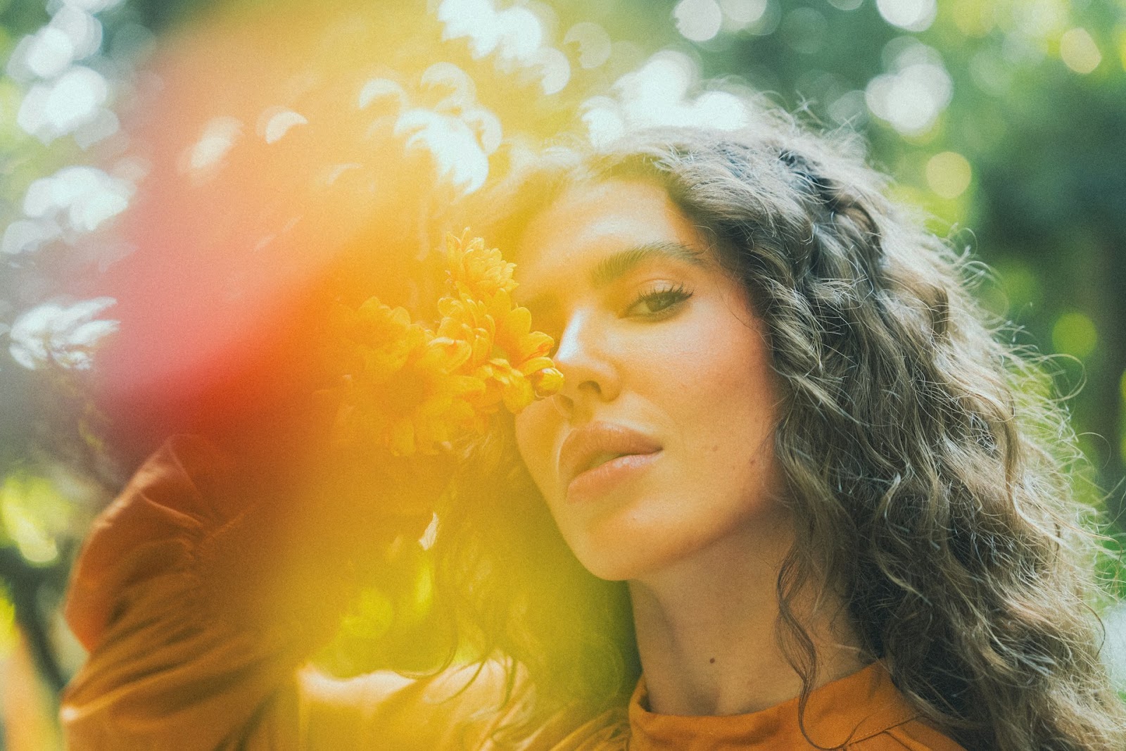 A woman posing outside next to a flower in the spring