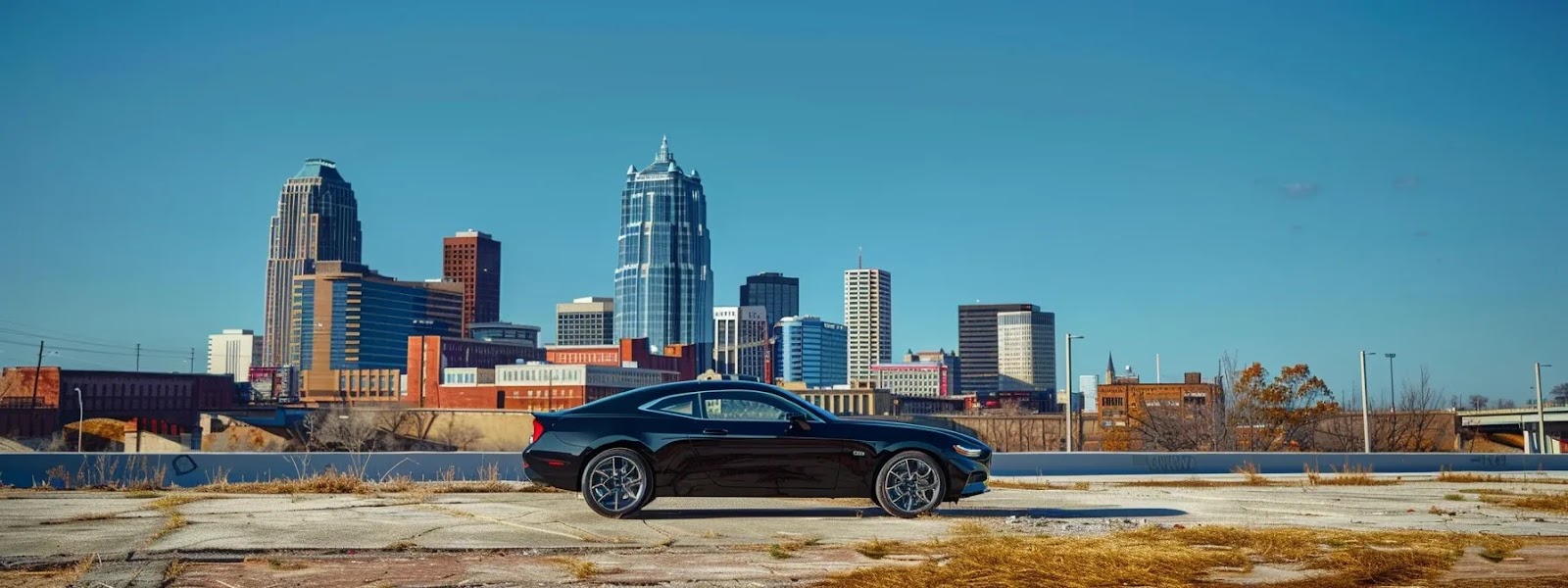 a sleek, black car parked in front of the tulsa skyline under a clear blue sky.