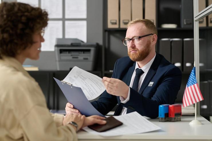 Portrait of bearded male consultant working in us embassy office and holding application form while