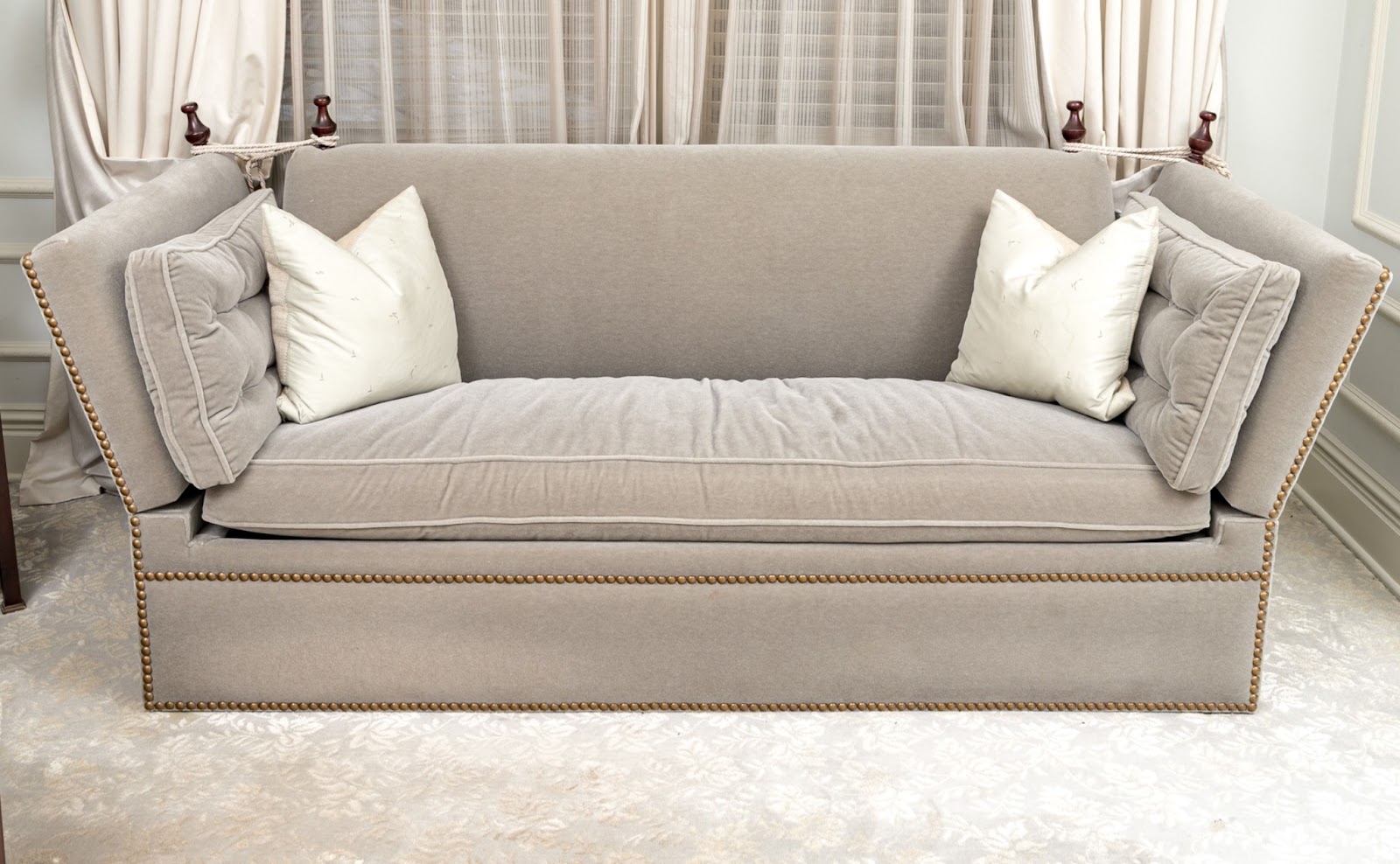 A light taupe-toned mohair upholstered sofa with drop-arms, nailhead trim, and upholstered pillows