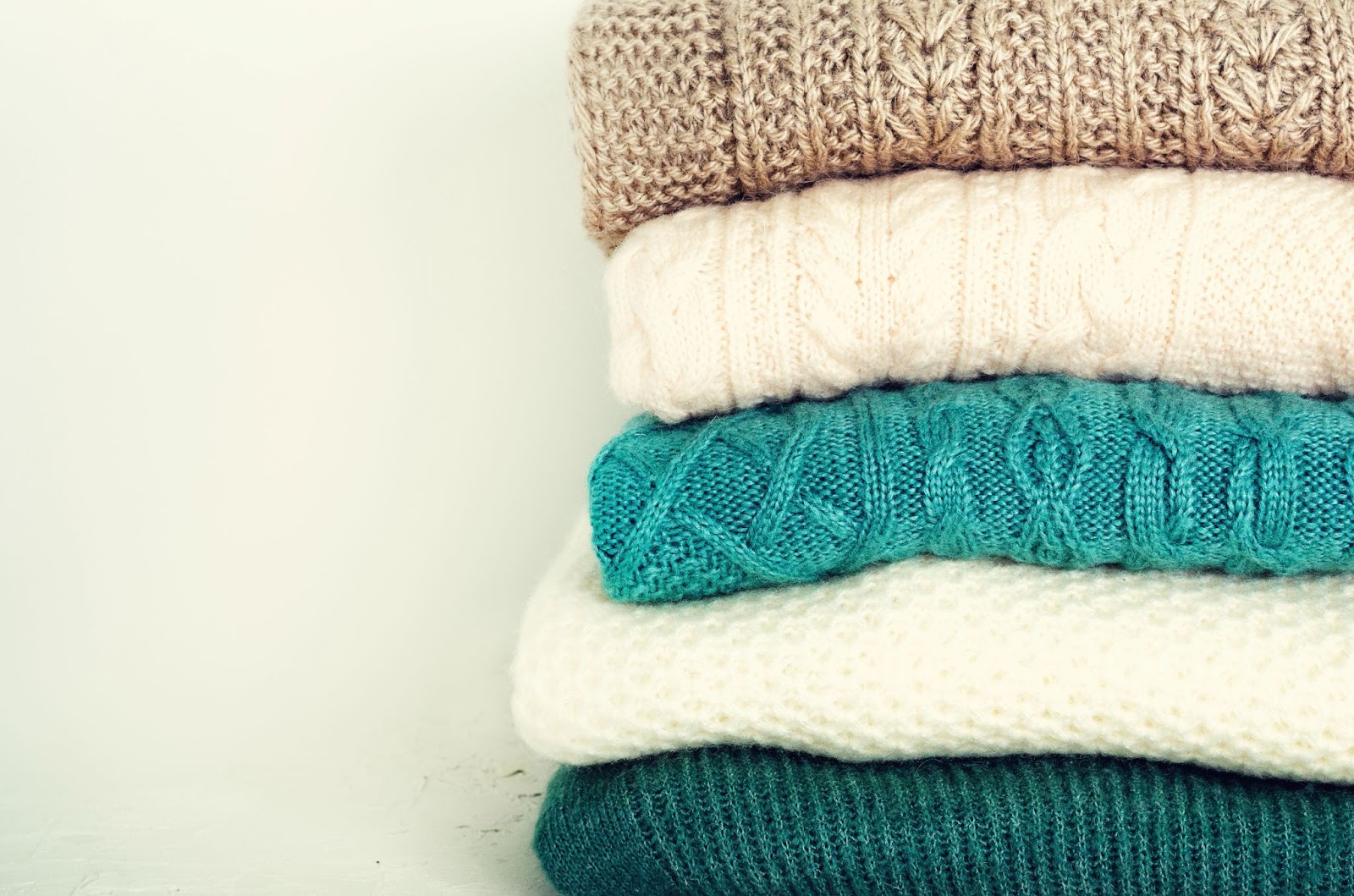 Neatly folded sweaters in a well-organized closet