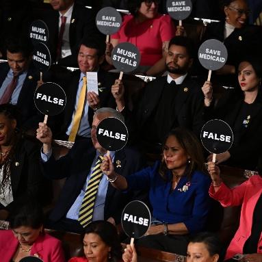 Democratic members of Congress holding round black signs that say “False,” “Save Medicaid” and “Musk Steals.”