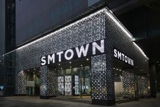 This may contain the entrance to smtown's store at night with its lights on and windows lit up