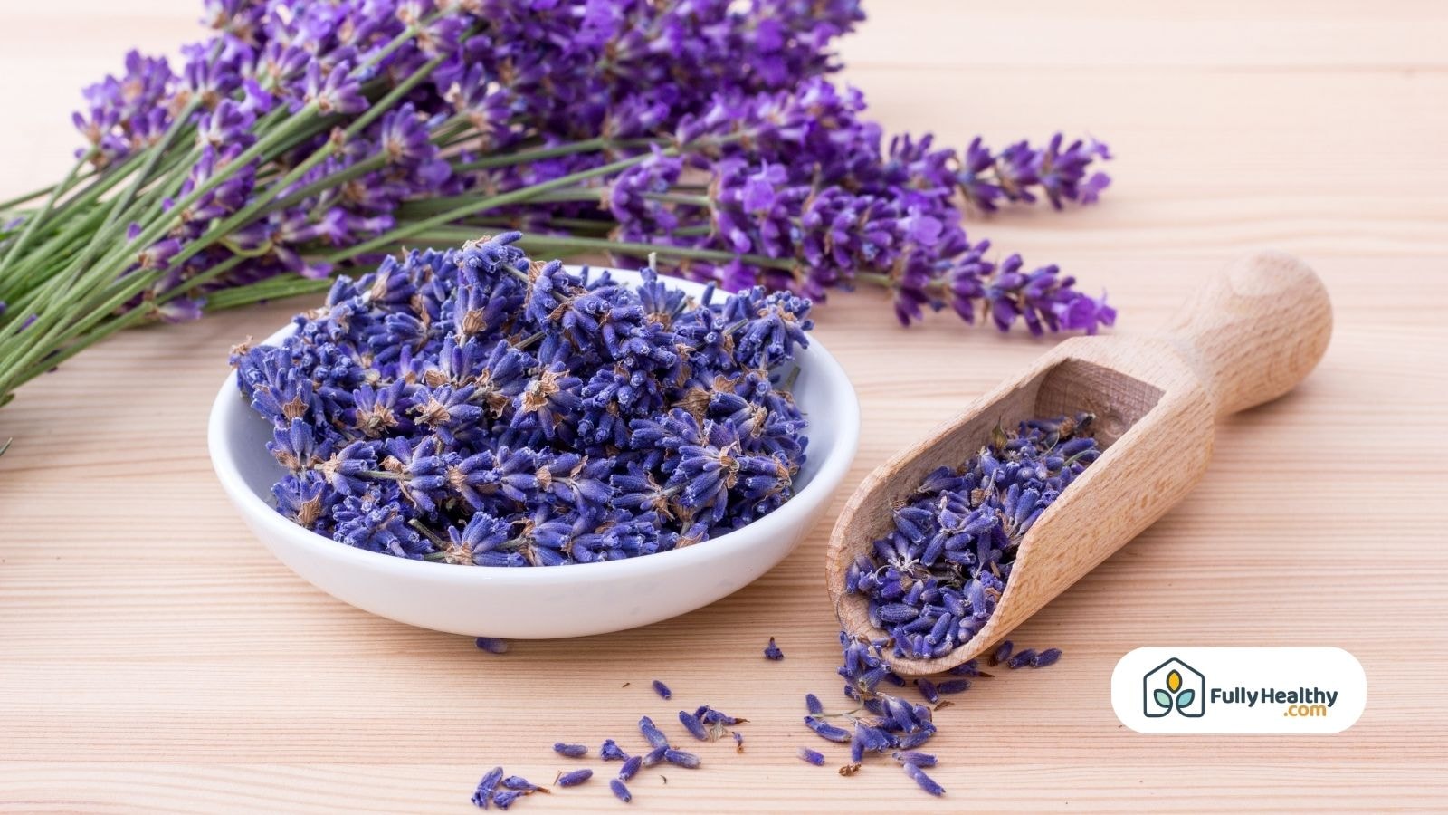 Bowl and scoop filled with dried lavender buds on wooden table