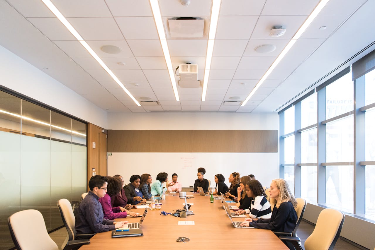 A diverse group of professionals seated at a long table during a meeting and using board portal software