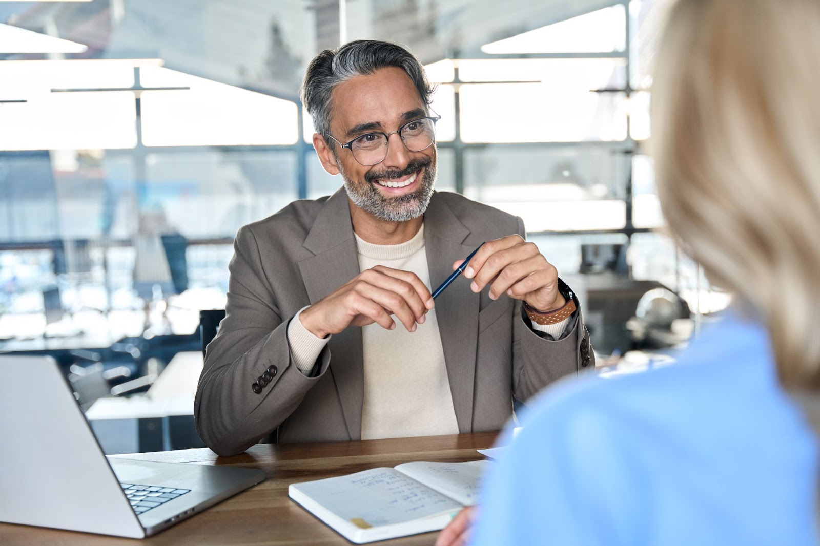 A smiling middle-aged financial advisor talks with a female client during an office meeting.