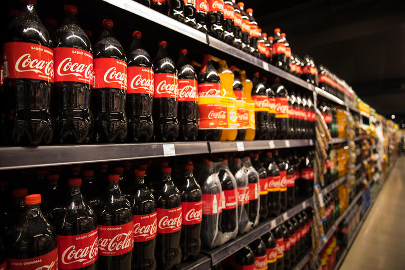 Rows of 2L Coca Cola bottles on supermarket shelves