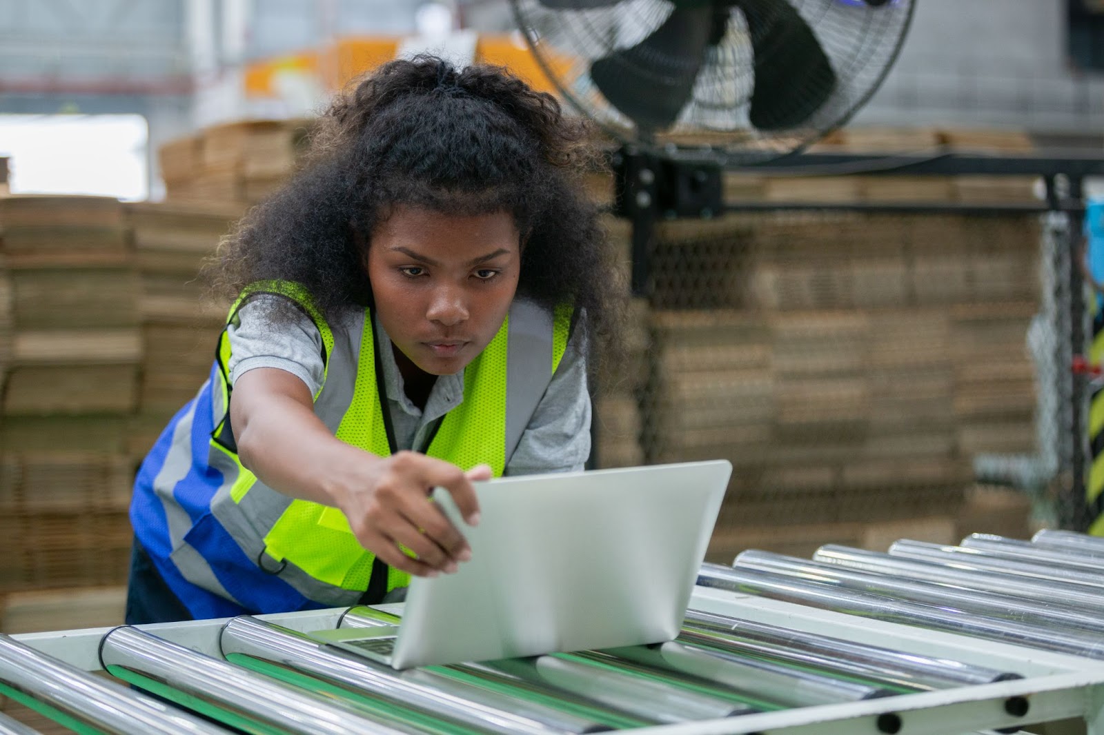 An African American woman uses software on her laptop to efficiently verify the quality and quantity of paper products in stock.