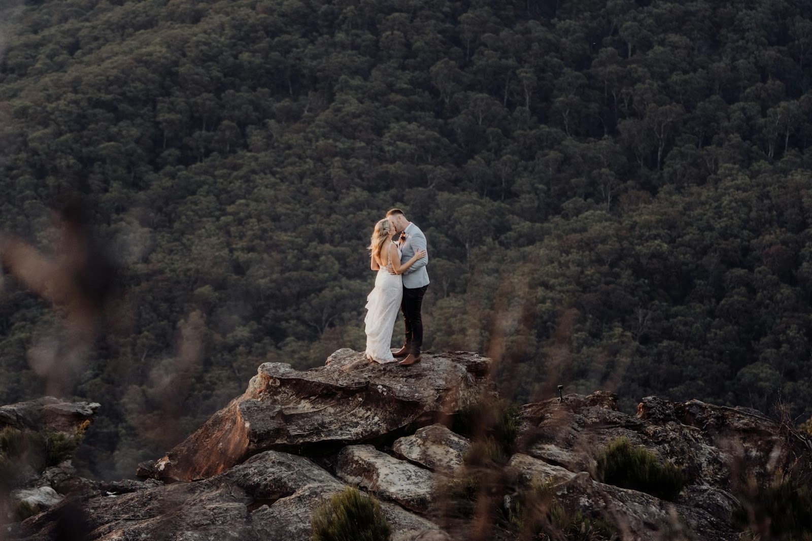 A person and person kissing on a rock

Description automatically generated