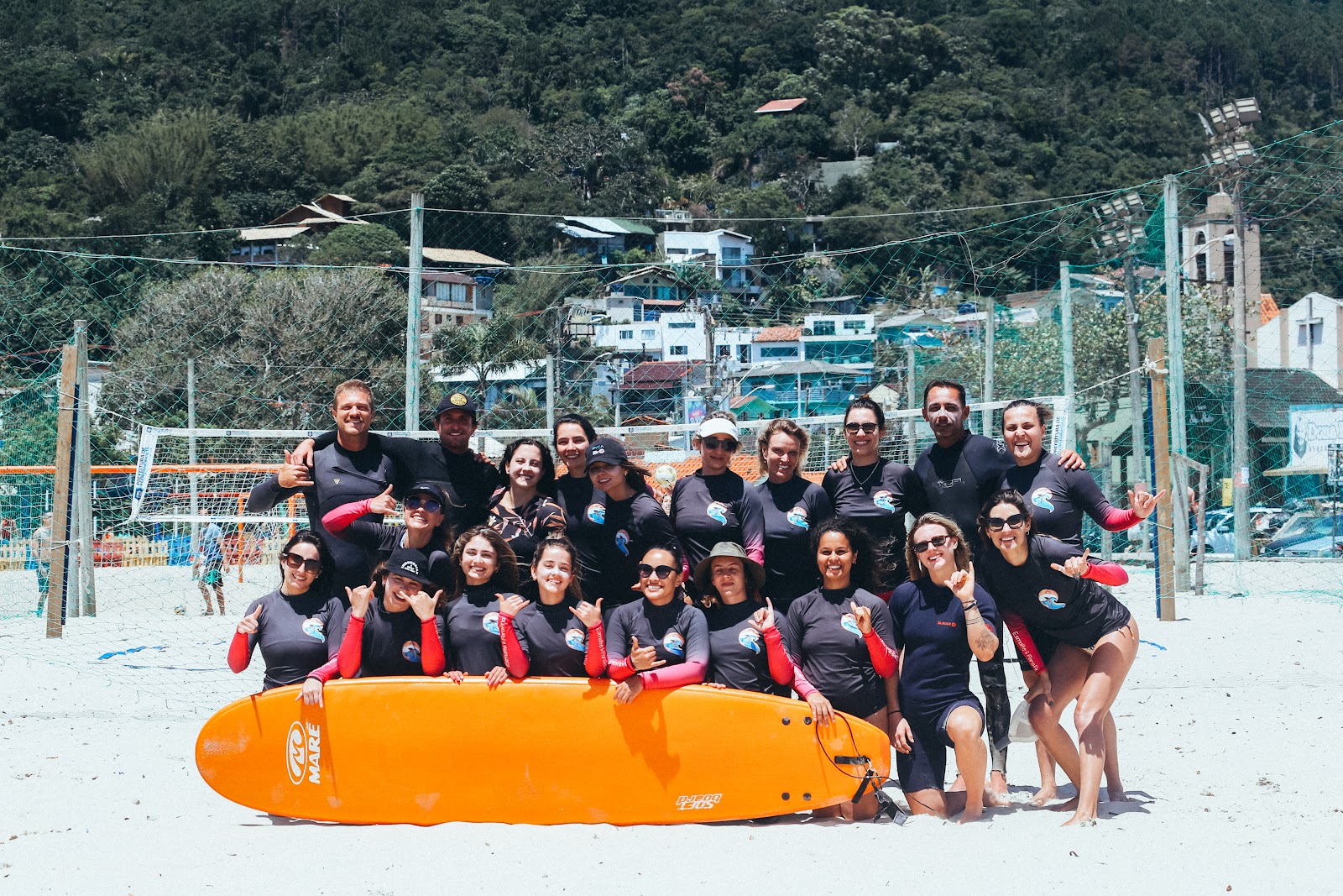 Foto de grupo de pessoas dantes de iniciarem a aula de surf. 