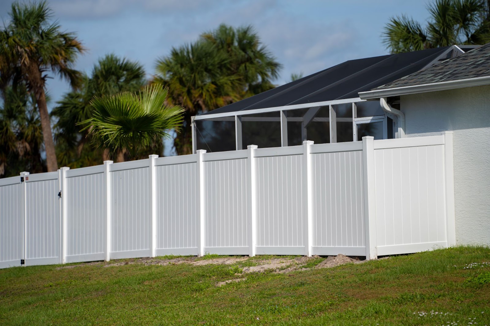 Vinyl fence with a gate around a house. 